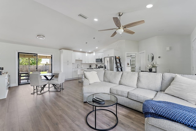 living room featuring light hardwood / wood-style floors, ceiling fan, lofted ceiling, and sink