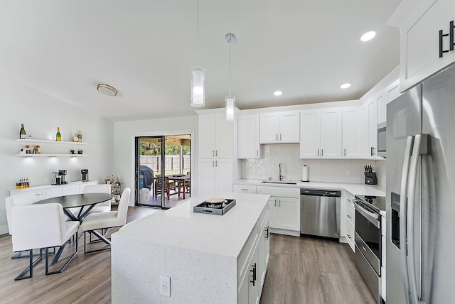 kitchen with white cabinetry, sink, decorative light fixtures, decorative backsplash, and appliances with stainless steel finishes