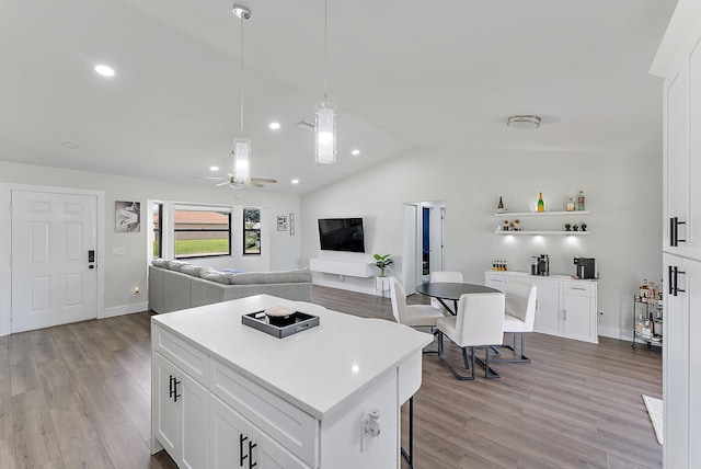 kitchen with white cabinetry, ceiling fan, light hardwood / wood-style floors, lofted ceiling, and a kitchen island