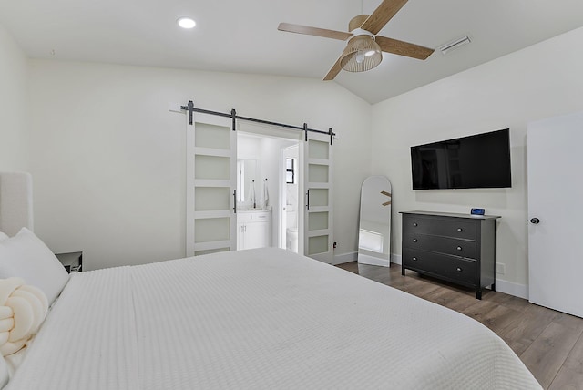 bedroom with ceiling fan, dark wood-type flooring, a barn door, connected bathroom, and lofted ceiling