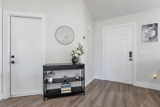 foyer entrance with wood-type flooring and lofted ceiling