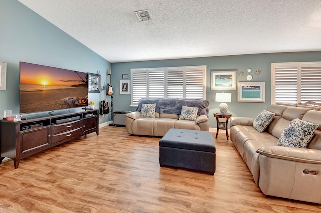 living room with vaulted ceiling, light hardwood / wood-style flooring, and a textured ceiling