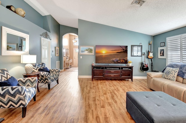 living room featuring vaulted ceiling, light hardwood / wood-style flooring, and a textured ceiling