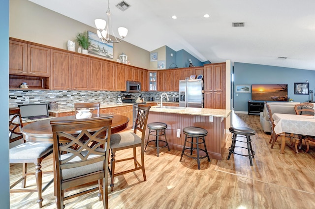 kitchen with sink, stainless steel appliances, lofted ceiling, and a notable chandelier