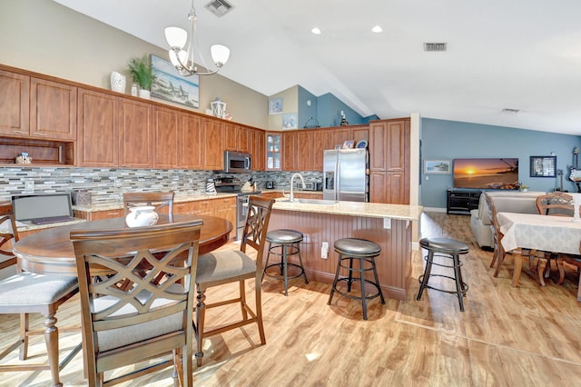 kitchen featuring stainless steel appliances, vaulted ceiling, tasteful backsplash, and a kitchen island with sink