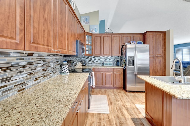 kitchen with backsplash, light stone counters, sink, and appliances with stainless steel finishes