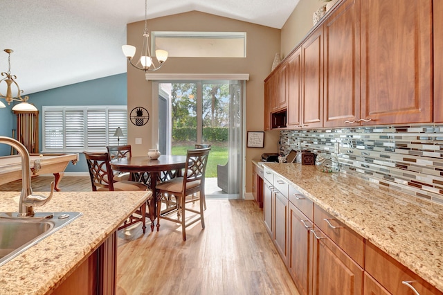 kitchen with decorative backsplash, decorative light fixtures, vaulted ceiling, and sink