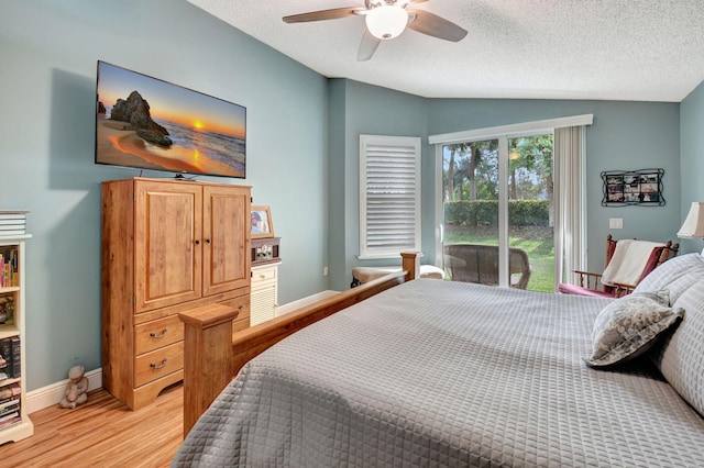 bedroom with ceiling fan, light wood-type flooring, a textured ceiling, and lofted ceiling