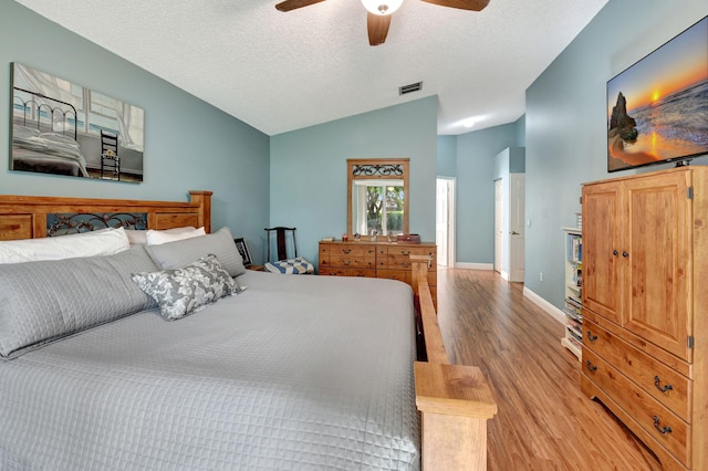 bedroom with a textured ceiling, light wood-type flooring, ceiling fan, and lofted ceiling