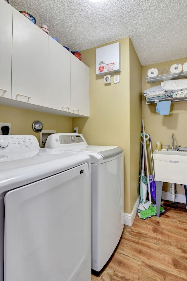 laundry area with washer and dryer, a textured ceiling, and cabinets