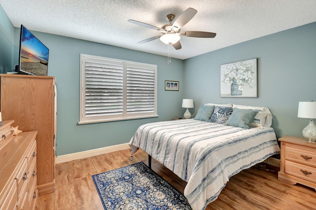 bedroom featuring ceiling fan, light wood-type flooring, and a textured ceiling