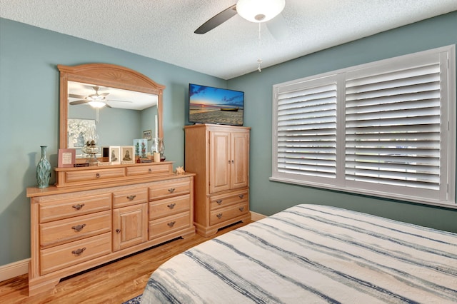 bedroom with a textured ceiling, light hardwood / wood-style floors, and ceiling fan