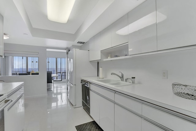 kitchen with dishwasher, white cabinets, a raised ceiling, sink, and light tile patterned floors