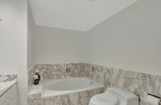 bathroom featuring tiled bath, vanity, and toilet