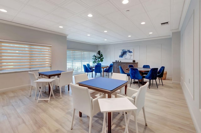 dining space with crown molding and light wood-type flooring