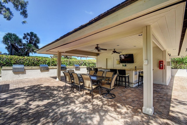 view of patio with ceiling fan, area for grilling, exterior kitchen, and an outdoor bar