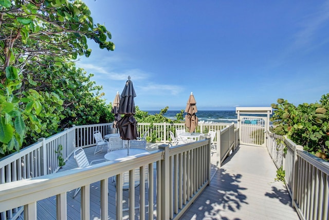 wooden deck featuring a water view and a view of the beach