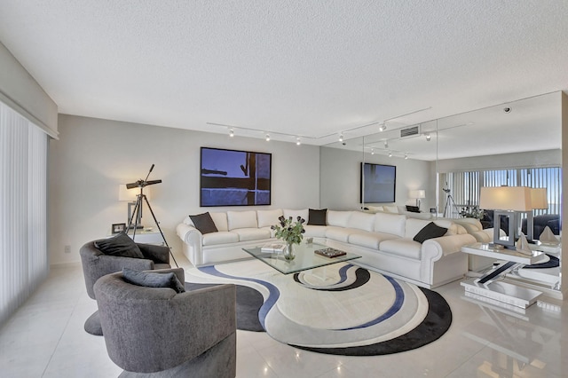 tiled living room featuring rail lighting and a textured ceiling