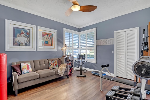 workout room featuring a textured ceiling, ceiling fan, light hardwood / wood-style floors, and crown molding