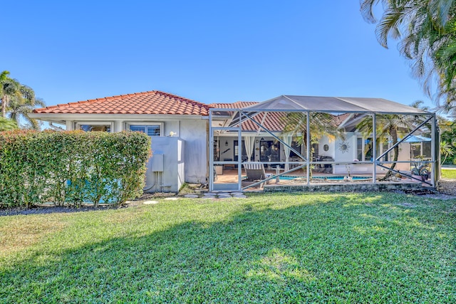 back of property featuring a lawn and glass enclosure