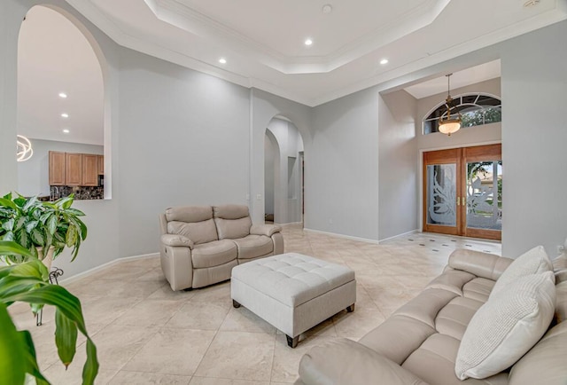 tiled living room featuring french doors, a tray ceiling, and ornamental molding