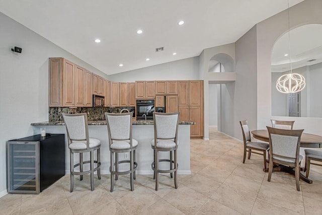 kitchen with a kitchen bar, backsplash, beverage cooler, and dark stone countertops