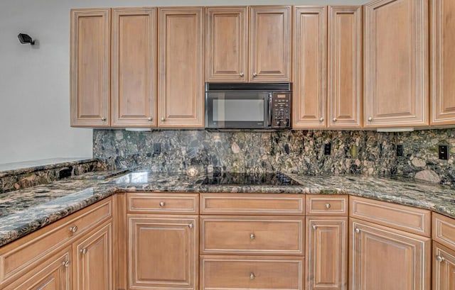 kitchen with backsplash, dark stone countertops, and black appliances