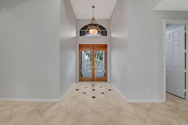 entrance foyer featuring light tile patterned flooring, a high ceiling, and french doors