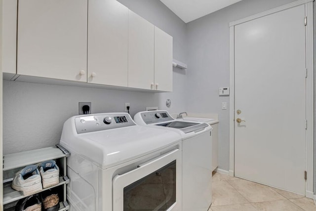 laundry area featuring washing machine and clothes dryer, sink, light tile patterned floors, and cabinets