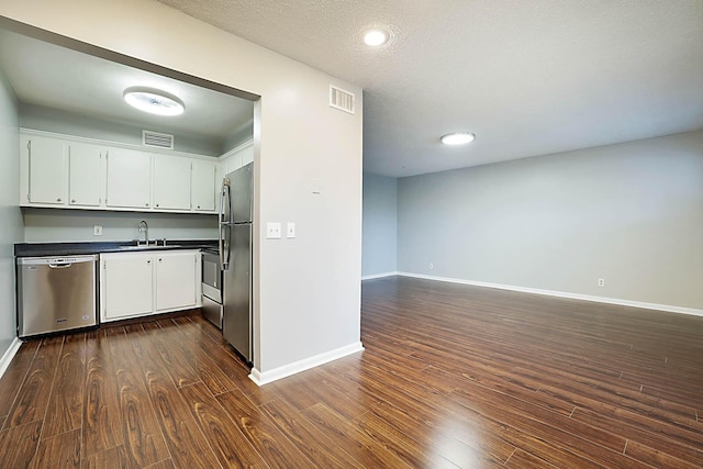 kitchen featuring a textured ceiling, white cabinetry, dark hardwood / wood-style floors, and appliances with stainless steel finishes