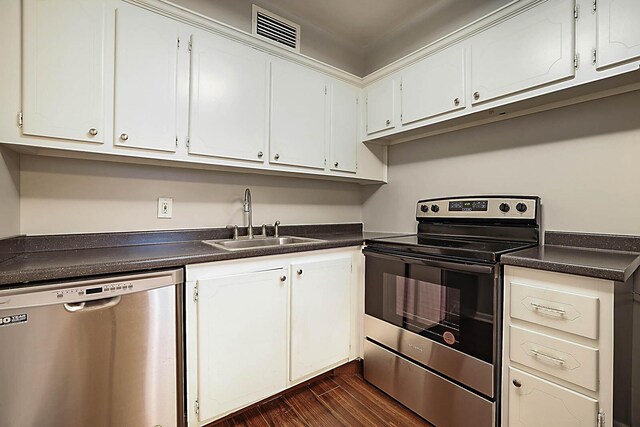 kitchen with stainless steel appliances, white cabinetry, dark wood-type flooring, and sink