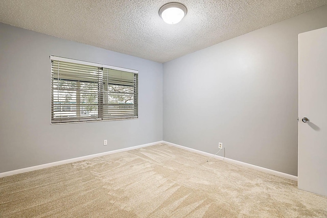 spare room featuring a textured ceiling and light colored carpet