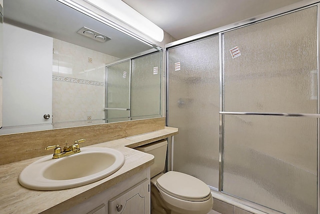 bathroom featuring a shower with door, vanity, and toilet