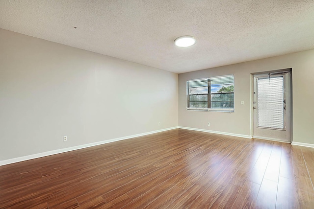 empty room with hardwood / wood-style floors and a textured ceiling