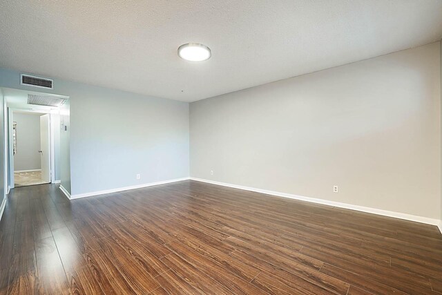 spare room featuring dark hardwood / wood-style flooring and a textured ceiling