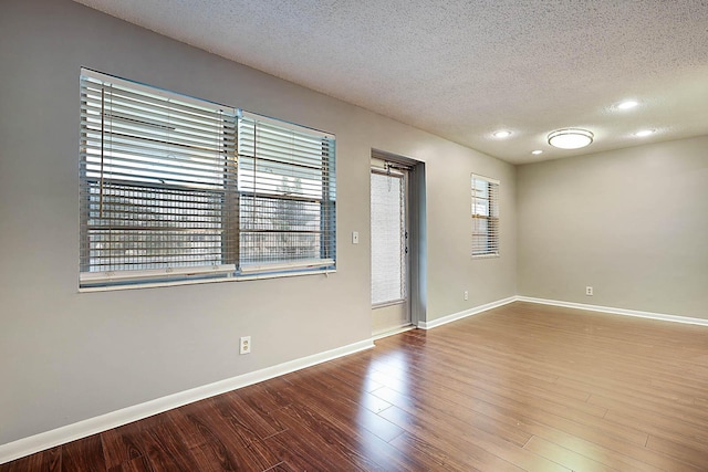 spare room with a healthy amount of sunlight, wood-type flooring, and a textured ceiling