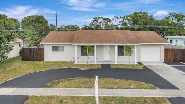 single story home featuring a porch, a garage, and a front lawn