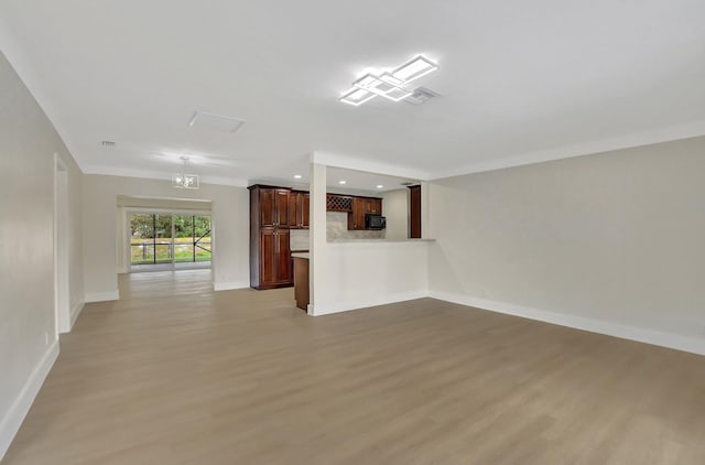 unfurnished living room with a notable chandelier and light hardwood / wood-style flooring