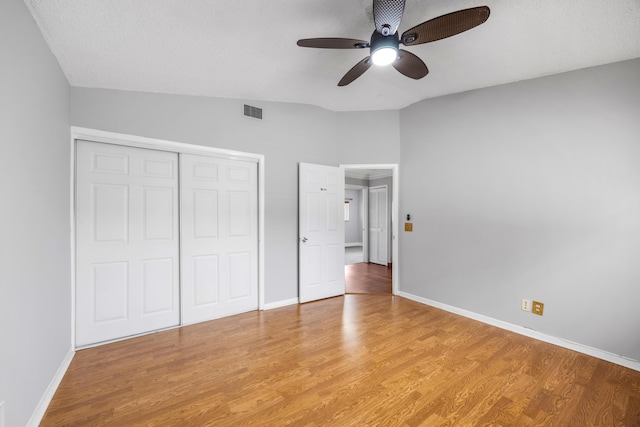 unfurnished bedroom with a textured ceiling, ceiling fan, wood-type flooring, a closet, and lofted ceiling