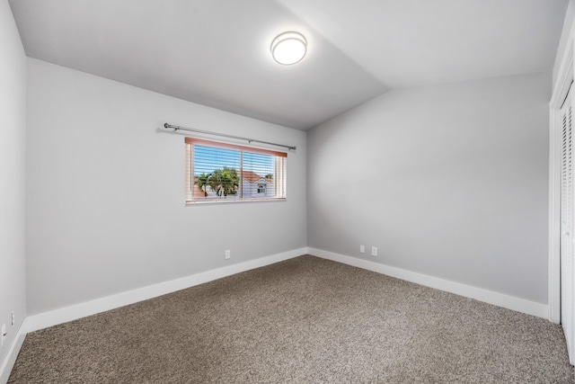 carpeted spare room with lofted ceiling