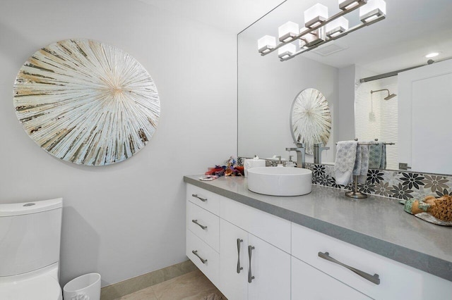 bathroom with tiled shower, vanity, and toilet