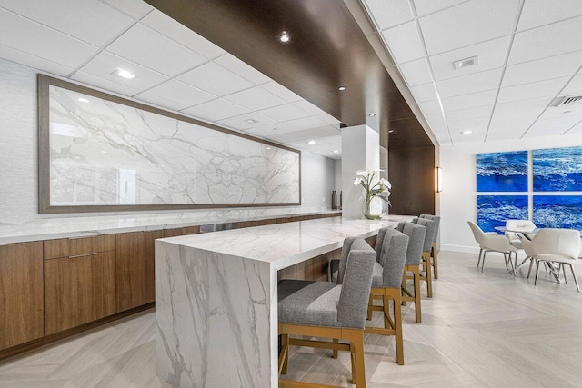 dining space with light parquet floors and a drop ceiling