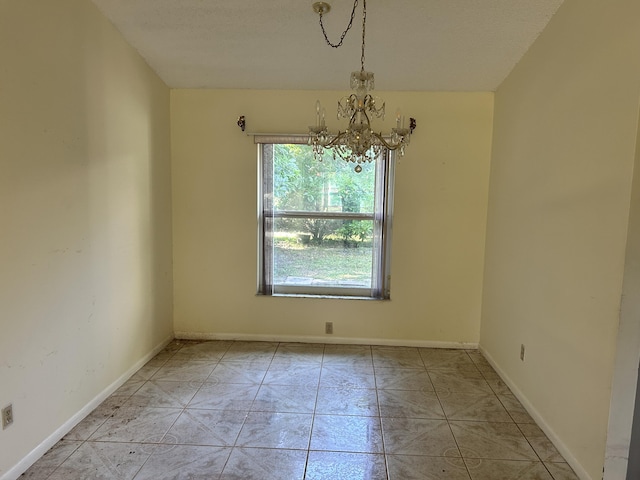 spare room featuring a chandelier and light tile patterned floors