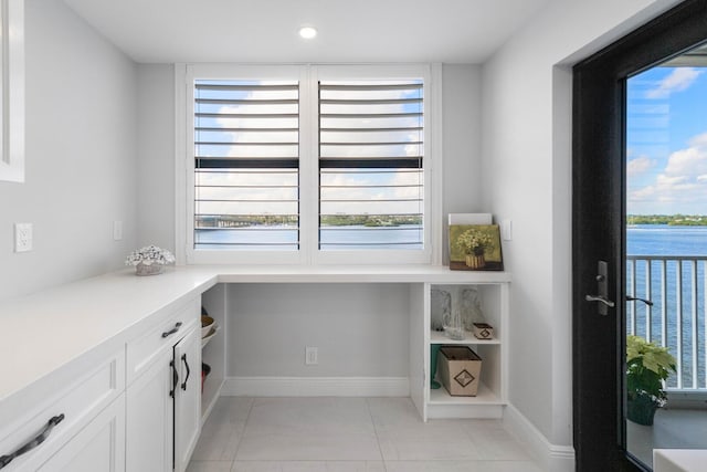 office space featuring light tile patterned floors, a healthy amount of sunlight, and a water view