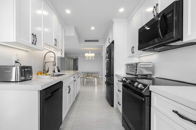 kitchen with black appliances, a notable chandelier, white cabinets, and sink