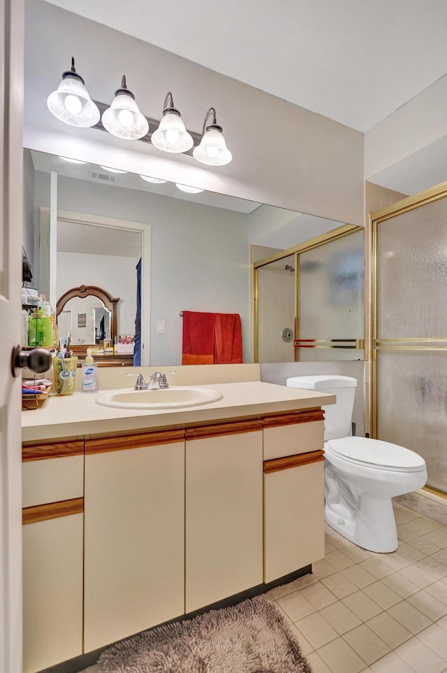 bathroom featuring tile patterned floors, vanity, toilet, and an enclosed shower