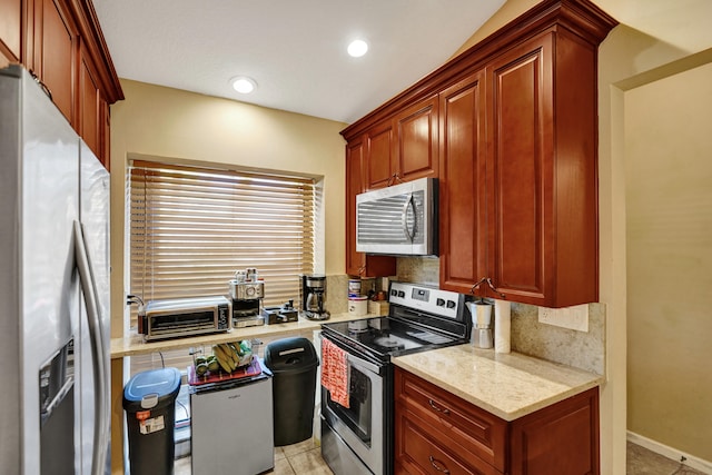 kitchen featuring light tile patterned flooring, light stone counters, stainless steel appliances, and tasteful backsplash