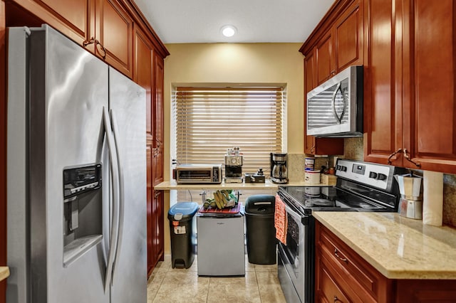 kitchen with light stone countertops, stainless steel appliances, and light tile patterned flooring