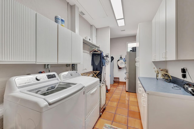 laundry room featuring washer and clothes dryer, cabinets, and light tile patterned flooring