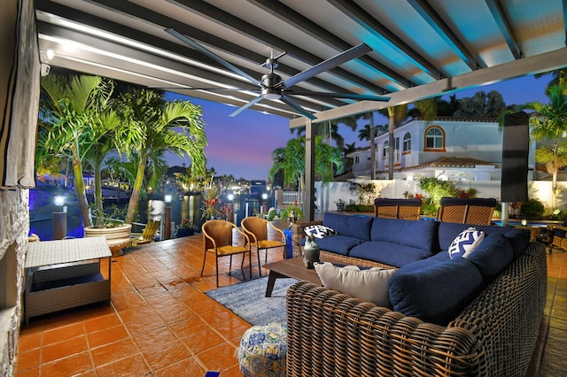 patio terrace at dusk featuring ceiling fan, an outdoor living space, and a pergola